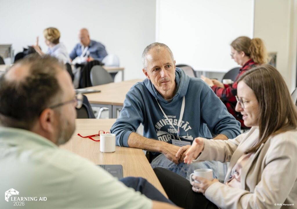 Learning AID Teilnehmer:innen unterhalten sich am Tisch mit Kaffee